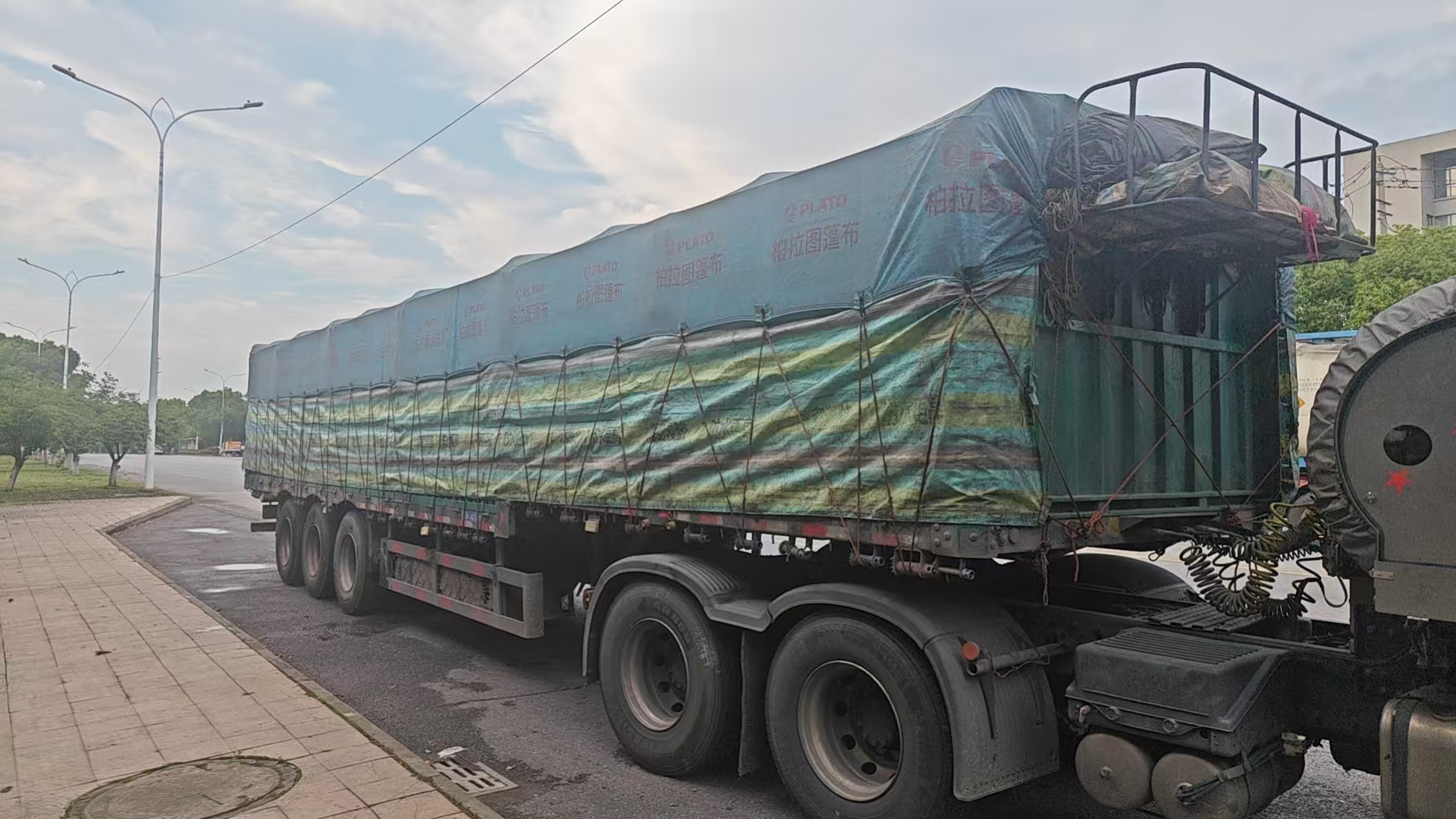 Sheeted flatbed trailer loaded with steel cargo at the factory in China