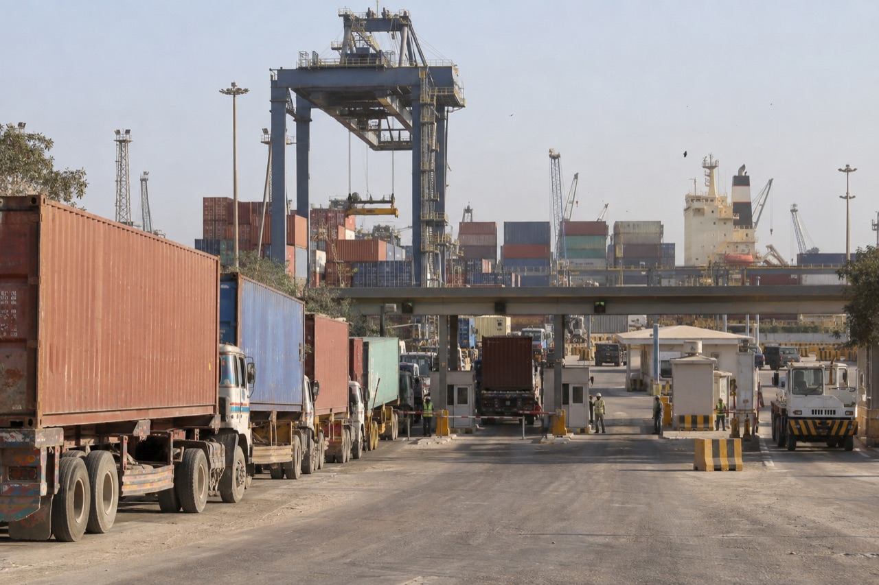 Illustrative image: a gantry crane and stacked containers at Port Qasim in Karachi with trucks waiting at the gate
