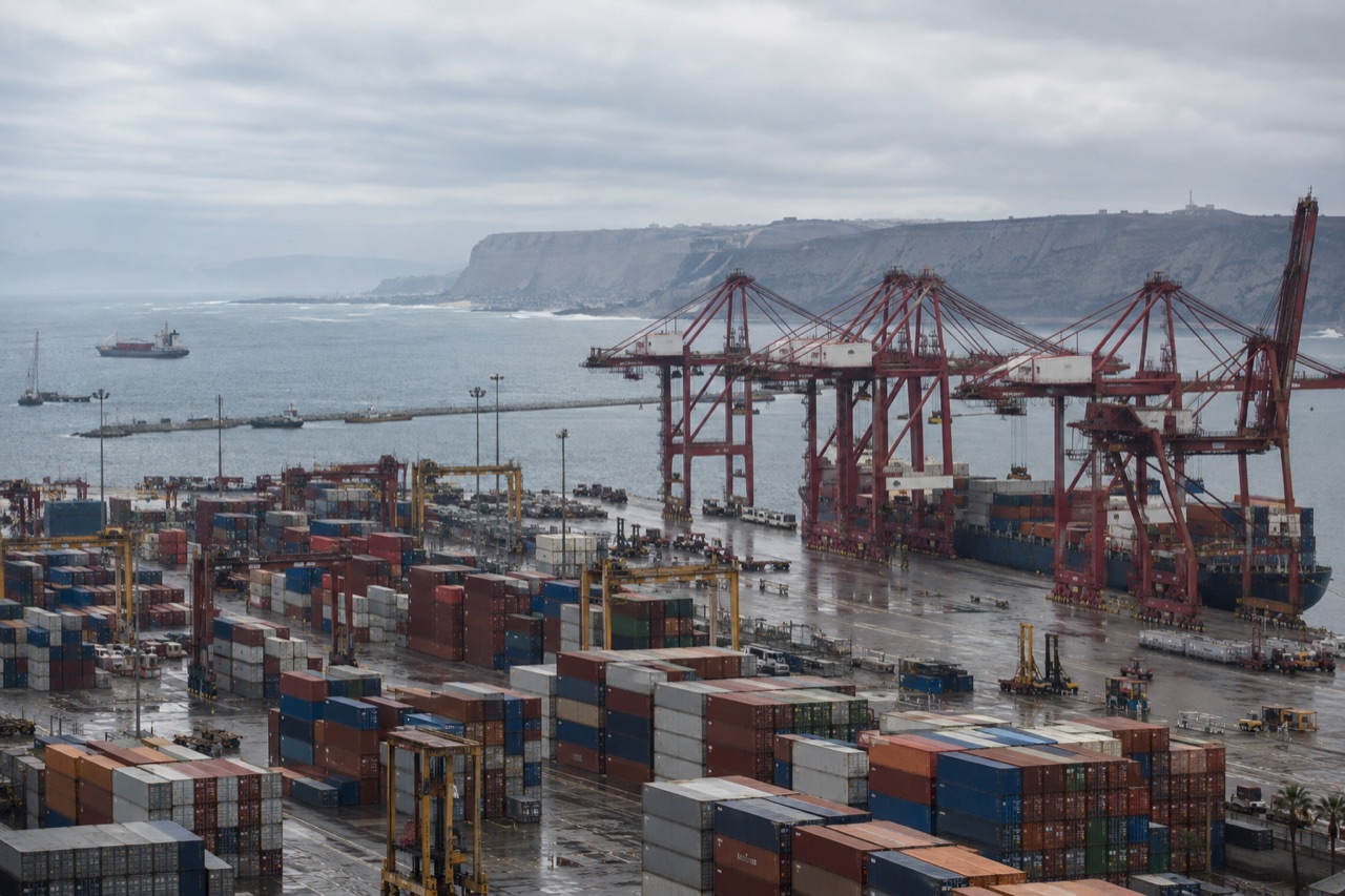 Illustrative image: container cranes at the Callao terminal beneath coastal cliffs under an overcast marine layer